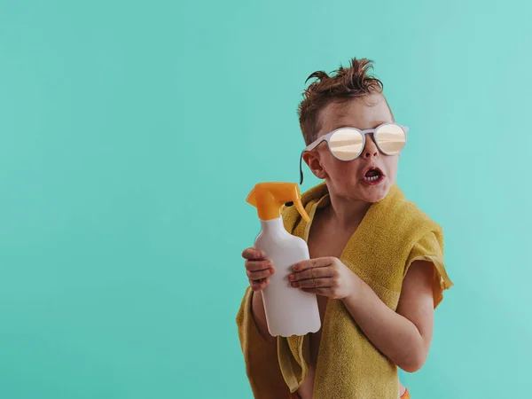 Happy child holding sunscreen lotion in hand. Summer vacation concept. Solar protection. Copy space, close up.