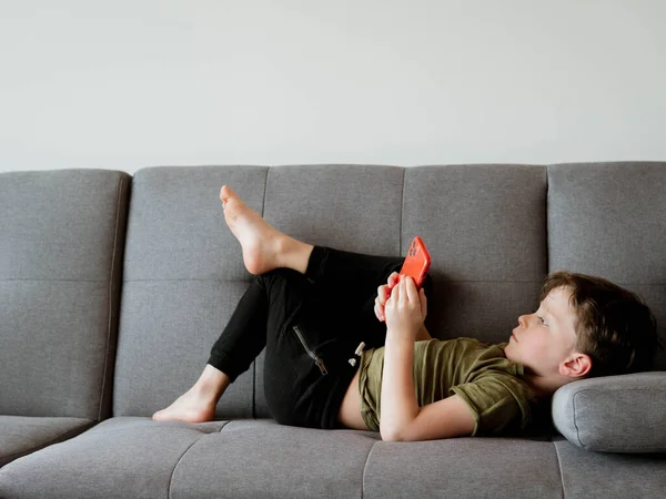 Little child with smart phone on sofa in room.