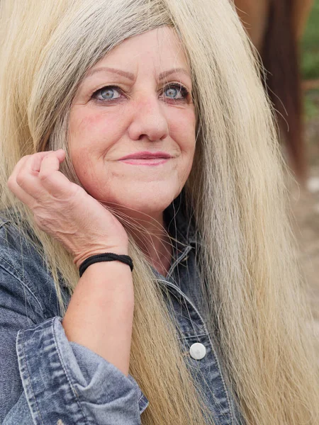 older woman putting on a horse\'s tail as a wig