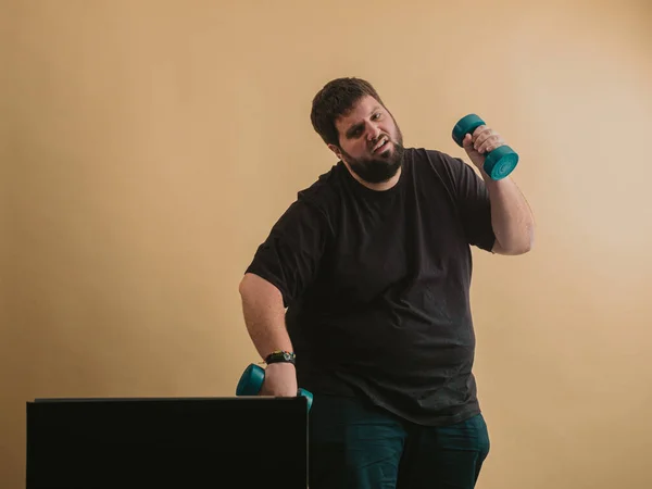 Obese man doing sports in an online class on computer