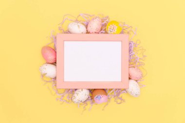 Paskalya yumurtalarının düz görünümü, modaya uygun sarı arka planda konfeti. Tebrik kartının en az tasarım modeli