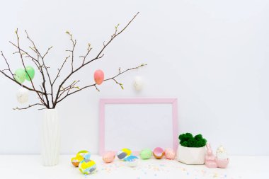 Paskalya yumurtalarını pembe Paskalya tavşanı ve ince dallarla birlikte moda renklerle boyadık. Boş fotoğraf çerçevesi modeli, metin için boşluk kopyala.