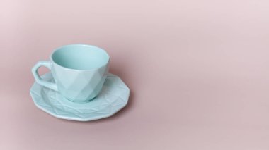 Açık mavi bardakla pembe zemin üzerinde fincan tabağı. Şık çanak çömlek. Seçici odak. 