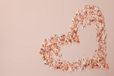 eart shaped pink himalayan salt scattered on a powder pink background. Copy space, top view. Healthy cooking, body care concept.  clipart