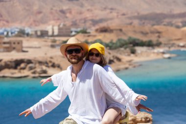 Mavi Kızıldeniz ve dağların arka planına uzanan baba ve kız turistler. Seyahat ve turizm kavramı. 