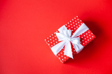 Kırmızı puantiyeli hediye kutusunda kırmızı arka planda beyaz fiyonk var. Uzayı kopyala, üst görünüm. Özel teklif, Kara Cuma, satış konsepti..