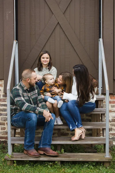 Una familia de cinco personas con dos niñas y un chico de bbay sentado en las escaleras en un lugar urbano del centro de la ciudad. —  Fotos de Stock