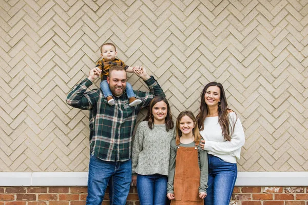 Pięcioosobowa rodzina z dwiema dziewczynami i małym chłopcem stojącym przed ceglanym śledziem. — Zdjęcie stockowe