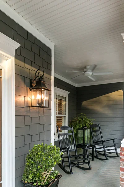 Un gran porche delantero de una casa gris de nueva construcción tradicional con mecedoras —  Fotos de Stock