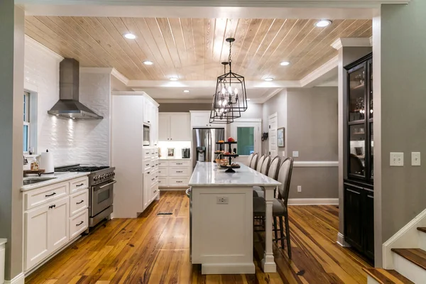 Ampia cucina bianca ristrutturata con piastrelle strutturate della metropolitana, luci in ferro nero e pavimenti in legno di pino — Foto Stock