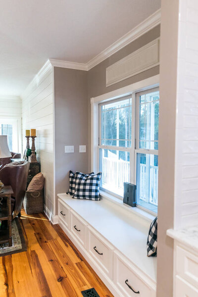 Большое оконное сиденье из белого дерева в новой пристройке гостиной