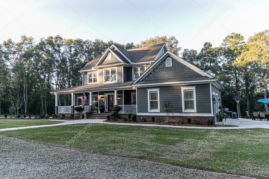 Front view of a large two story blue gray house with wood and vinyl siding
