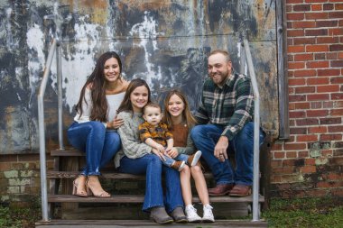 Beş kişilik bir aile, iki kız ve bir çocuk şehir merkezindeki basamaklarda oturuyor..