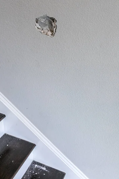 A hole in the wall of a stairwell caused by a fist punching through the wall