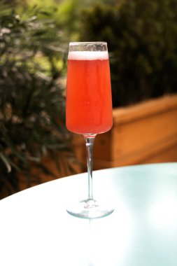 Çilekli mimoza dışarıda bir lokanta masasında yeşil çalılarla kahvaltı için bekliyor.