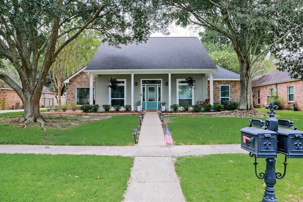 A front view of an Acadian renovated home with columns, sidewalks and a colorful front door recently purchased with the changing real estate market