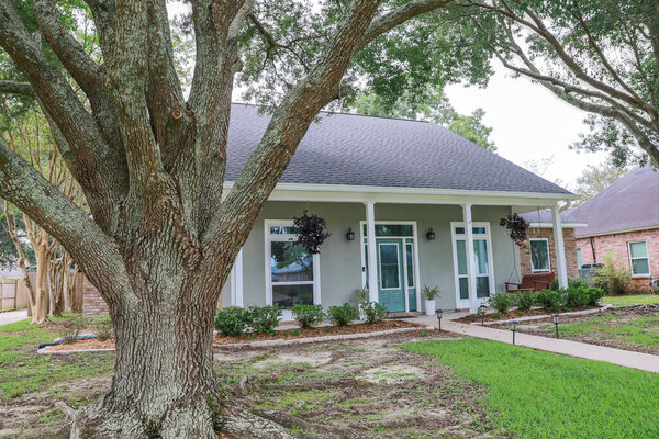 A front view of an Acadian renovated home with columns, sidewalks and a colorful front door recently purchased with the changing real estate market