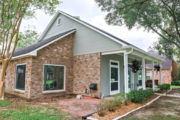 Uma vista frontal e lateral inclinada de uma casa renovada acadiana com colunas, calçadas e uma porta da frente colorida recentemente comprada — Fotografia de Stock