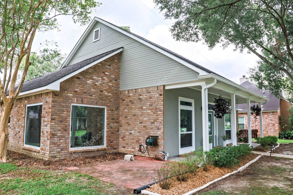 An angled front and side view of an Acadian renovated home with columns, sidewalks and a colorful front door recently purchased