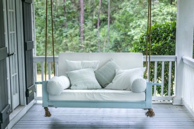 A luxurious and classic outdoor bed swing painted a seafoam green with white deep cushions clipart