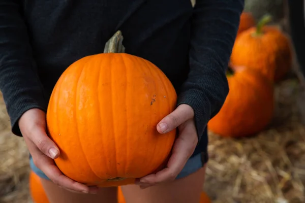 Mujer sosteniendo calabaza naranja calabaza en el festival local de otoño — Foto de Stock