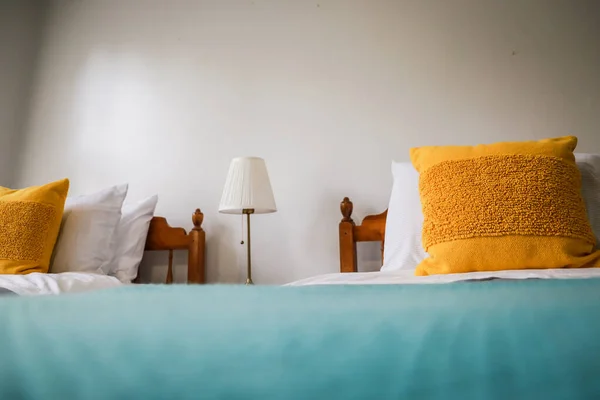Спальня с двумя односпальными кроватями с бирюзовыми и серыми покрывалами и желтыми декоративными подушками — стоковое фото