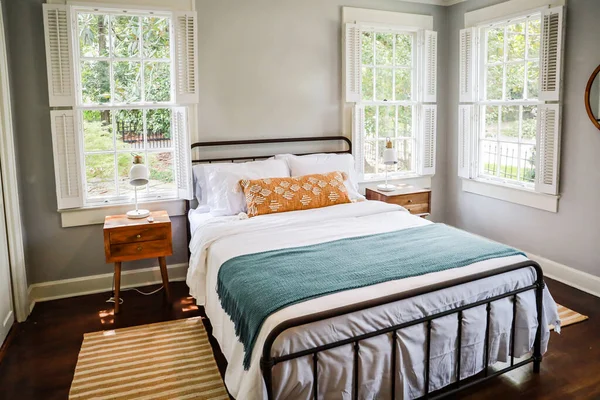 Гостевая спальня с двуспальной кроватью и тумбочкой в краткосрочной аренде домик в стиле коттеджа — стоковое фото