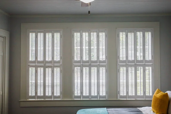 Три больших окна со ставнями для плантаций кремового цвета, которые закрыты на интерьере коттеджного дома — стоковое фото