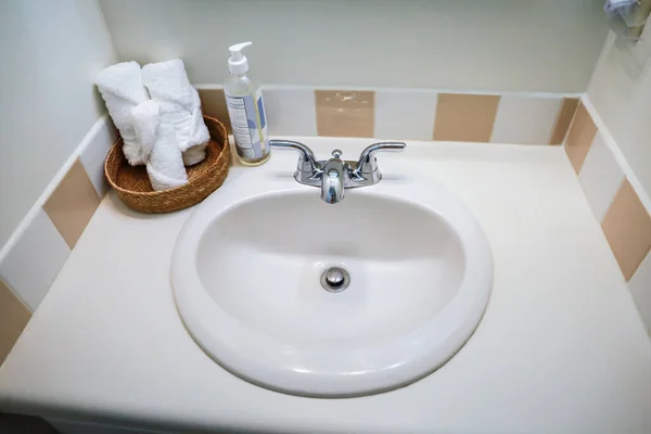 Weißes Waschbecken mit Vintage-Fliesen und zusammengerollten Handtüchern im Gästebad des alten Ferienhauses. — Stockfoto