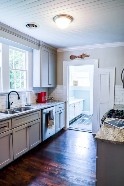 Malá kuchyňka s šedými skříněmi a tmavými podlahami z tvrdého dřeva v krátkodobém nájemním domě — Stock fotografie