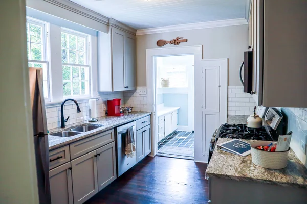 Небольшая кухня с маленькими шкафами и темными деревянными полами в доме краткосрочной аренды — стоковое фото