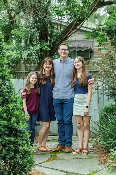 Una familia de una madre y un padre y dos hijas de pie en el patio trasero de una casa al aire libre en el verano o el otoño —  Fotos de Stock