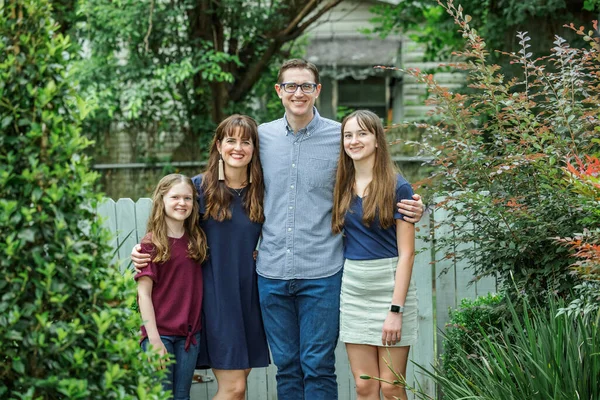Una familia de una madre y un padre y dos hijas de pie en el patio trasero de una casa al aire libre en el verano o el otoño —  Fotos de Stock