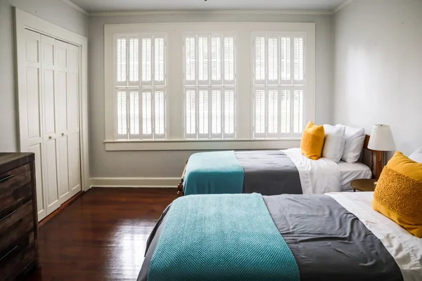 Sypialnia z dwoma łóżkami pojedynczymi z turkusowymi i szarymi narzutami i żółtymi poduszkami dekoracyjnymi — Zdjęcie stockowe