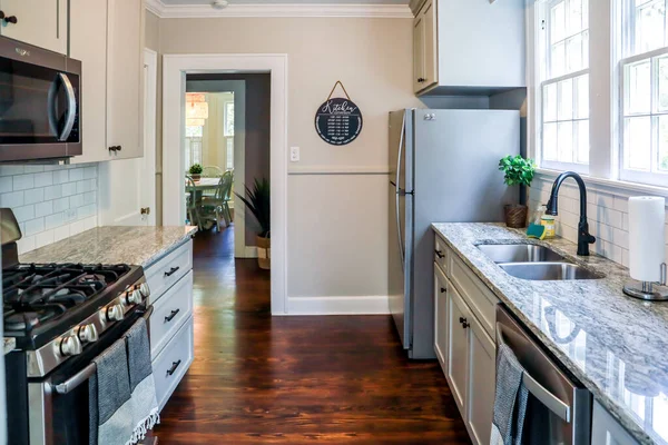 Una pequeña cocina con armarios grises y pisos de madera oscura en una casa de alquiler a corto plazo — Foto de Stock