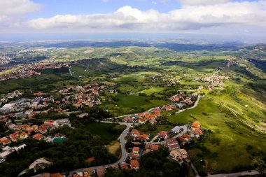 İtalya 'nın San Marino kentindeki Titano Dağı' ndaki Guaita Kalesi 'nin tepesinden panoramik manzara güneşli bir günde bulutlarla kaplı güzel mavi gökyüzü. Denize, San Marino köylerine ve Rimini 'ye bakın.,