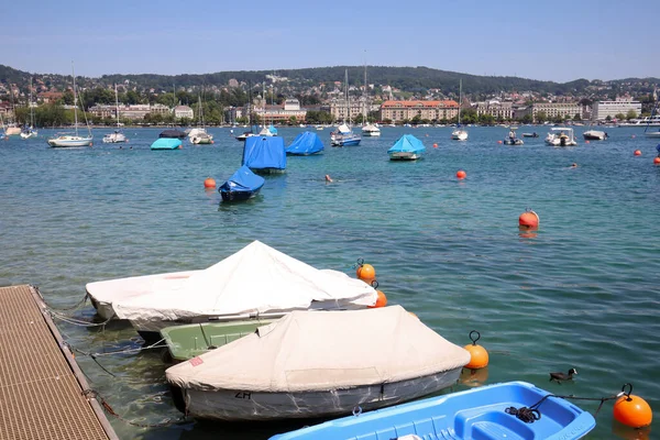 Zürih, İsviçre, 23 Temmuz 2019 Zürih gölündeki kırmızı şamandıralar ve tekneler. Güneşli yaz gününde limana demirli tekneler ve arka planda binalar