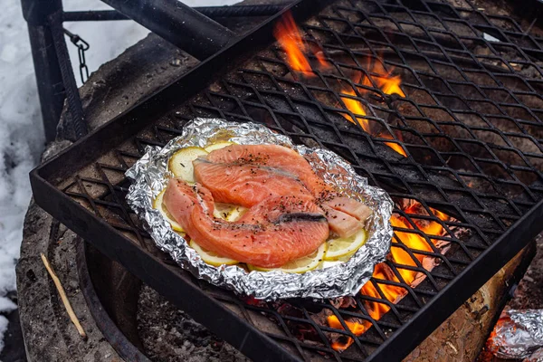 Pieces of salmon on slices of lemon on foil are grilled over a fire. — Stock Photo, Image