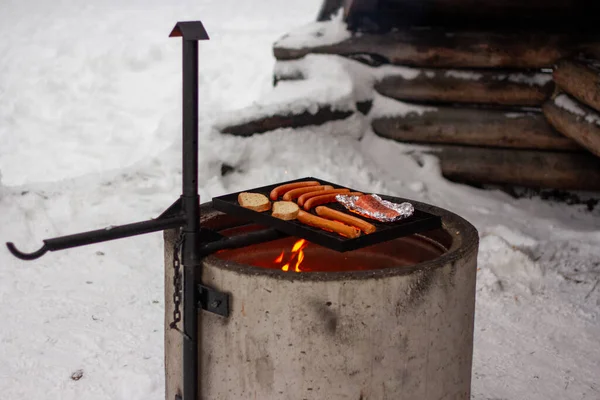 Lazac, kolbász és kenyér a grillen a tűz felett. — Stock Fotó