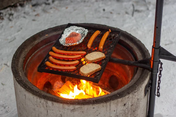 Lazac, kolbász és kenyér a grillen a tűz felett. — Stock Fotó