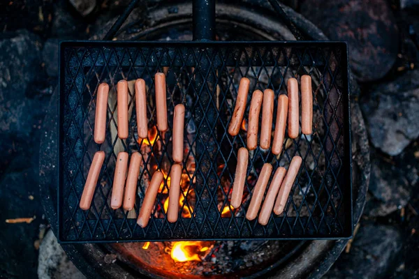 The sausages are grilled on the grid over a campfire. — Stock Photo, Image