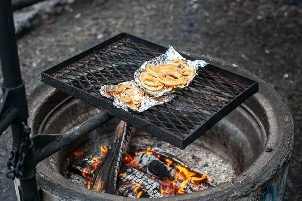 Le cipolle sono grigliate sulla lamina di metallo sopra un falò. — Foto Stock