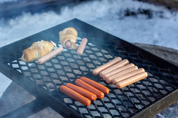 Kolbász és kolbászos zsemle grillsütőn a tűz felett. — Stock Fotó