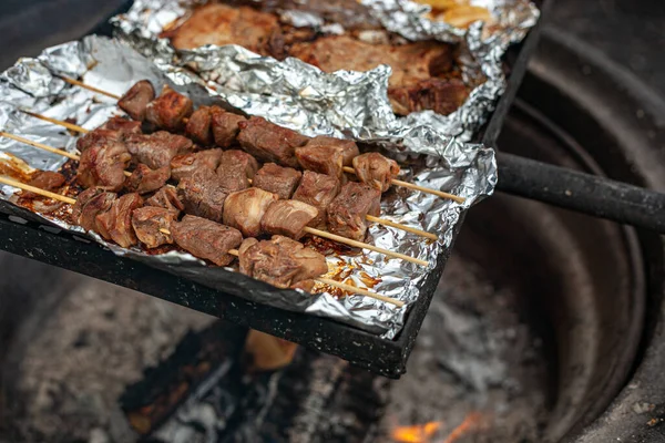 Kebab de cerdo, filetes de cerdo y cebollas se asan a la parrilla en el papel de aluminio sobre una fogata. — Foto de Stock