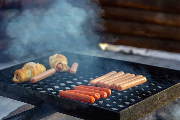 Salsicce e focacce di salsiccia su una griglia barbecue su un fuoco. — Foto Stock