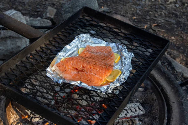 Los filetes de salmón se asan a la plancha en la rejilla de hierro sobre un fuego. — Foto de Stock