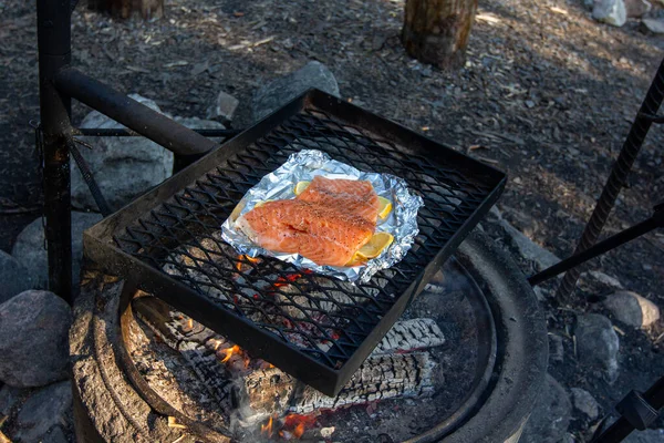 Lachsfilets werden auf Folie auf dem Eisengitter über dem Feuer gegrillt. — Stockfoto