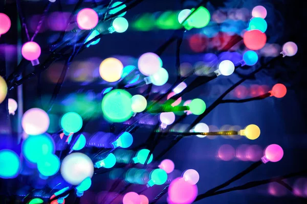 Glowing colorful Christmas lights on dark background. Defocused — Stock Photo, Image