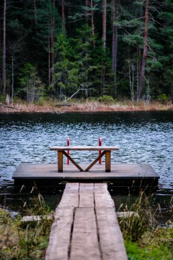 Ormandaki sonbahar gölündeki yaya köprüsü. Sonbahar havası. Dikey fotoğraf