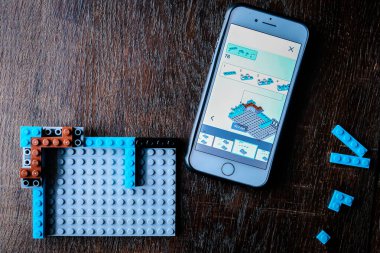 Riga, Letonya - 26 Aralık 2020: Lego ile oynayan çocuk, plastik inşaat oyuncakları ve talimatlar için akıllı telefonu kullanıyor. Seçici odak